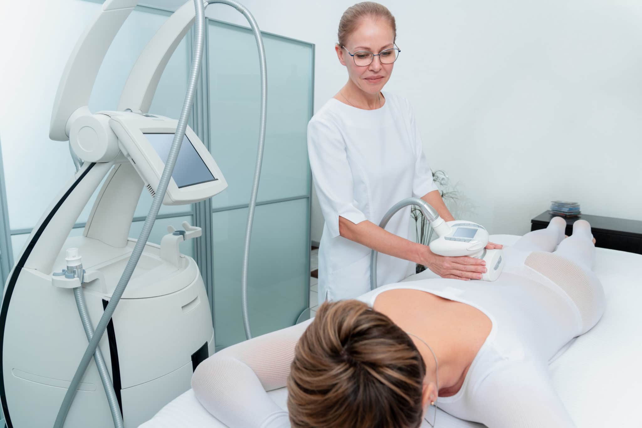 Woman in special white suit getting anti cellulite massage in a spa salon. LPG, and body contouring treatment in clinic