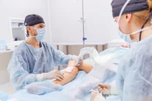 doctor and an assistant in the operating room for surgical venous vascular surgery clinic